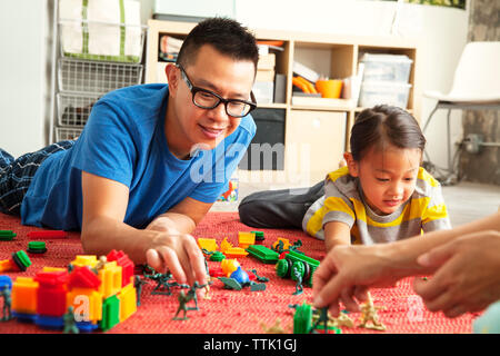 Father and children playing with toys on floor at home Stock Photo