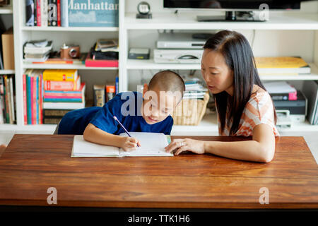 High angle view of mother assisting son in homework while sitting at home Stock Photo