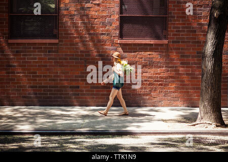 Full length of woman walking on sidewalk against building Stock Photo