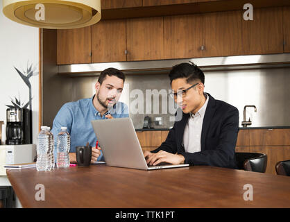 business partners talking over laptop computer at creative office Stock Photo