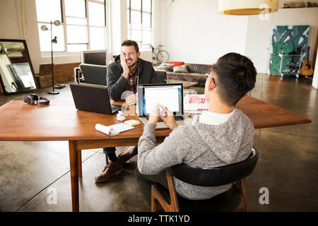 business partners talking while using laptops at table in office Stock Photo