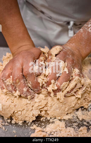 Midsection of man kneading dough at commercial kitchen Stock Photo