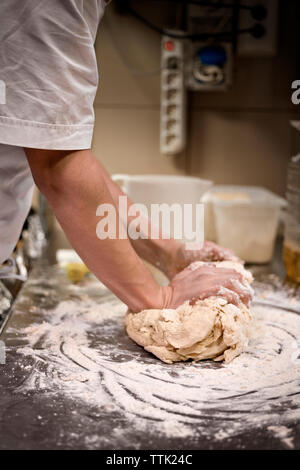 Cropped image of man kneading dough at commercial kitchen Stock Photo