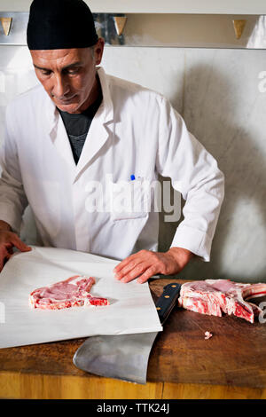 Butcher wrapping fresh meat for sale at shop Stock Photo