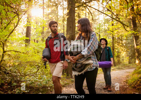Friends talking while walking in forest Stock Photo