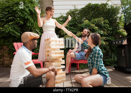 Happy friends playing large toy block in lawn Stock Photo
