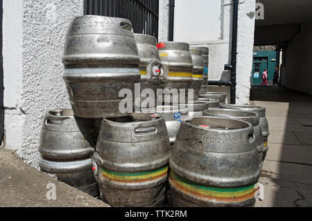 Close up of empty metal alumnium aluminum beer barrels stacked up outside a pub England UK United Kingdom GB Great Britain Stock Photo