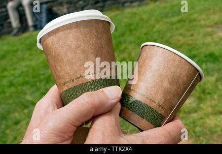 Close up of hands man person holding a disposable drinking cup cups made from plants England UK United Kingdom GB Great Britain Stock Photo