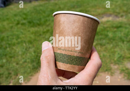 Close up of hand person man holding a disposable compostable paper recycling drinking tea coffee cup made from plants England UK Britain Stock Photo