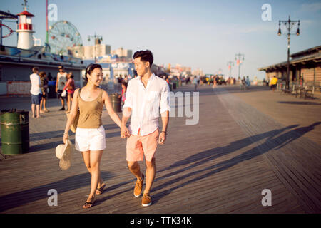 Couple holding hands while walking on pier Stock Photo