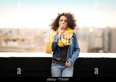 Woman smoking while standing on building terrace Stock Photo
