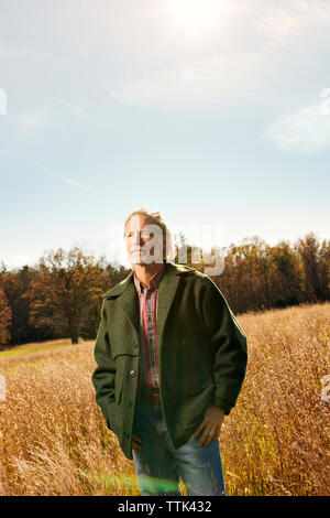 Thoughtful man standing amidst field against sky Stock Photo