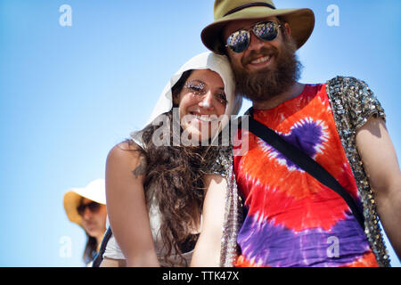 Low angle view of cheerful man and woman standing against clear sky at traditional event Stock Photo
