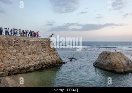Boys jumping from Galle Fort into the shallow water of Galle Baty, Galle, Sri Lanka Stock Photo