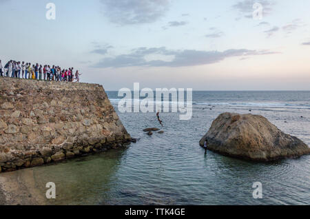 Boys jumping from Galle Fort into the shallow water of Galle Baty, Galle, Sri Lanka Stock Photo
