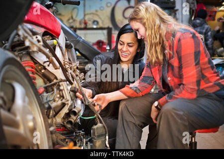Happy female mechanics repairing bike in workshop Stock Photo