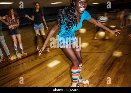 Happy woman enjoying with friends at roller rink Stock Photo