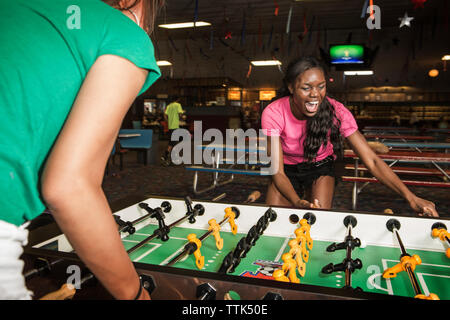 Friends enjoying foosball at club Stock Photo
