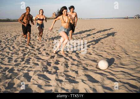 Happy friends playing soccer at beach on sunny day Stock Photo