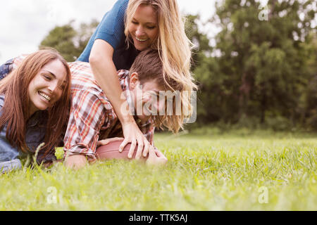 Happy friends playing football on grassy field Stock Photo