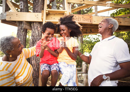 Grandparents enjoying with grandchildren on tree house Stock Photo