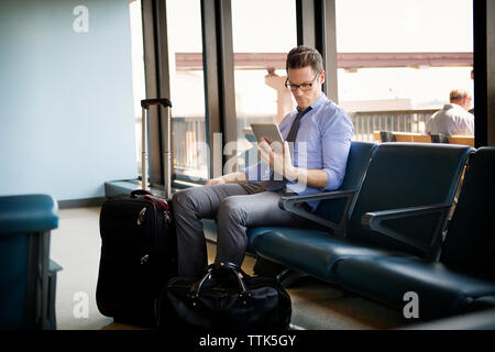 businessman using tablet computer while sitting in waiting area at subway station Stock Photo