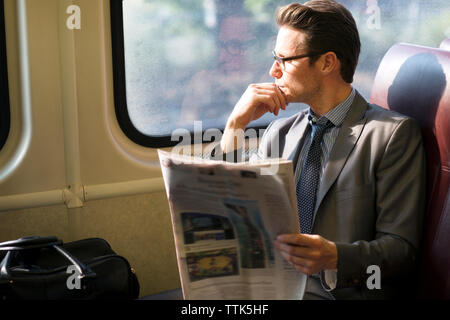 Thoughtful businessman holding newspaper while traveling in train Stock Photo