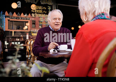 Thoughtful senior man sitting with woman at sidewalk cafe Stock Photo