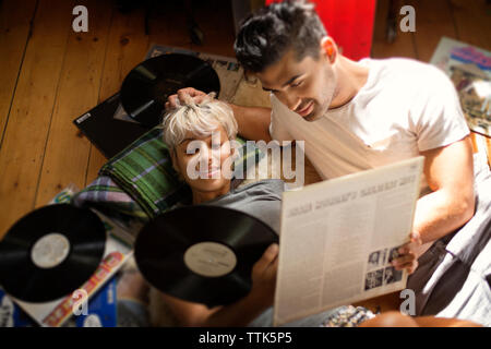 Overhead view of couple looking at vinyl records while lying on floor Stock Photo