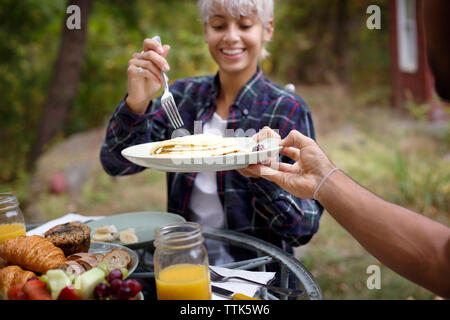 Cropped image of man offering pancakes to young woman during breakfast Stock Photo