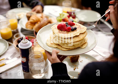 Cropped image of woman holding pancakes at breakfast table Stock Photo