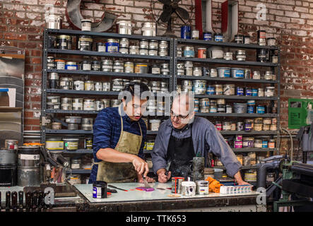 workers mixing colors using ink knife on table at workshop Stock Photo