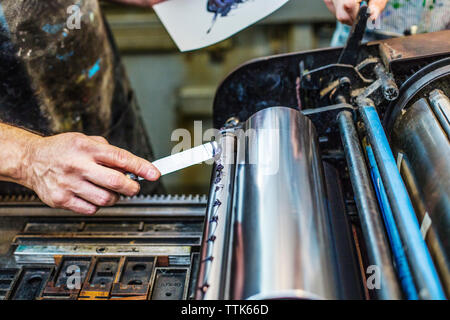 Cropped image of worker applying blue ink on printing roller at workshop Stock Photo