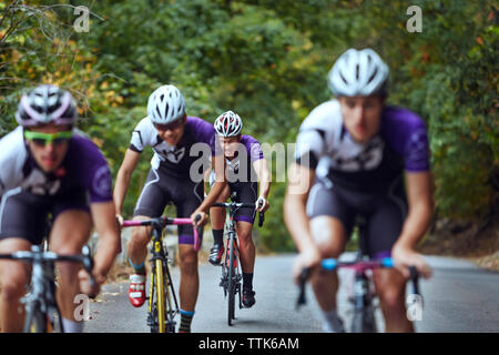 Male athletes friends riding bicycles on road Stock Photo