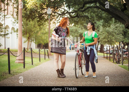 Happy friends walking with bicycle on footpath Stock Photo