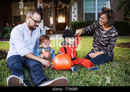 Happy family sitting on grass at backyard Stock Photo