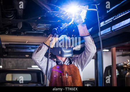 Mechanic welding car in auto repair shop Stock Photo