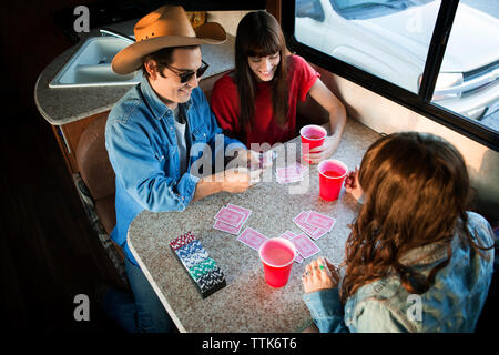 High angel view of friends playing cards at table while travelling in camper van Stock Photo