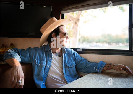 Thoughtful man sitting by window in camper van Stock Photo