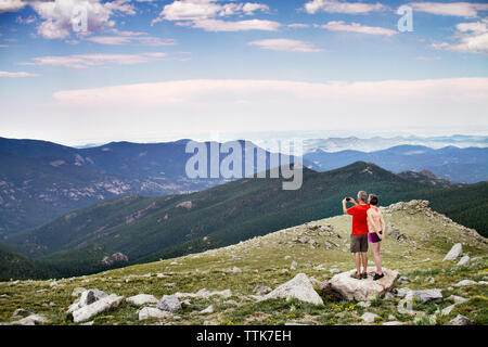 Rear view of couple photographing while standing on rock Stock Photo