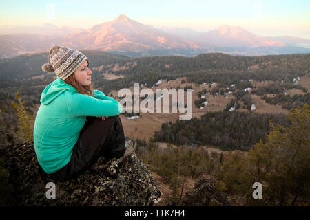 Woman sitting on mountain against sky Stock Photo