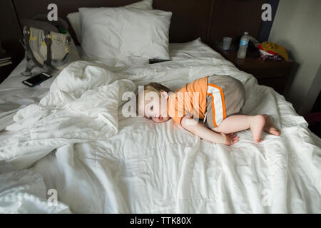 High angle view of thoughtful tired baby boy lying on bed at home Stock Photo