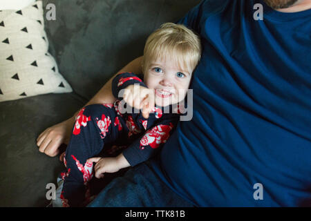 Happy toddler boy points while sitting next to Dad on couch Stock Photo