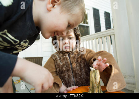 Two children examine pumpkin on front porch during Halloween Stock Photo