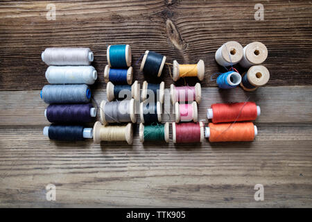 Overhead view of various thread spools on wooden table Stock Photo