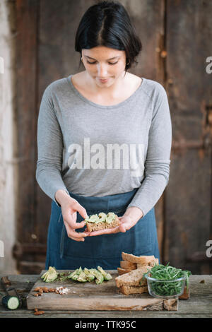 Woman making sandwich on wooden table at home Stock Photo
