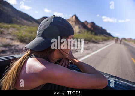 Young Woman Enjoying Mountain View from back of truck Stock Photo