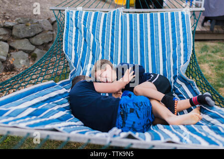 High angle view of cheerful brothers playing in hammock Stock Photo