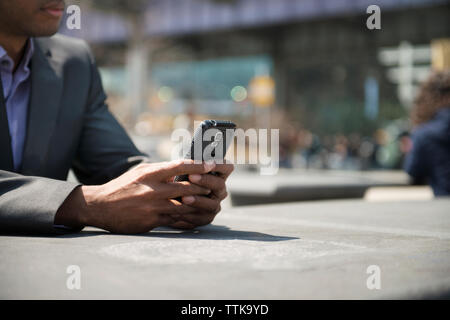 Cropped image of businessman using smart phone on table Stock Photo