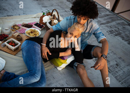 High angle view of couple relaxing on rooftop during sunset Stock Photo